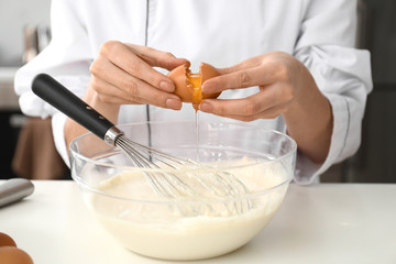 Young female confectioner making dough in kitchen