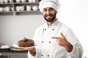 Male confectioner with tasty chocolate cake in kitchen