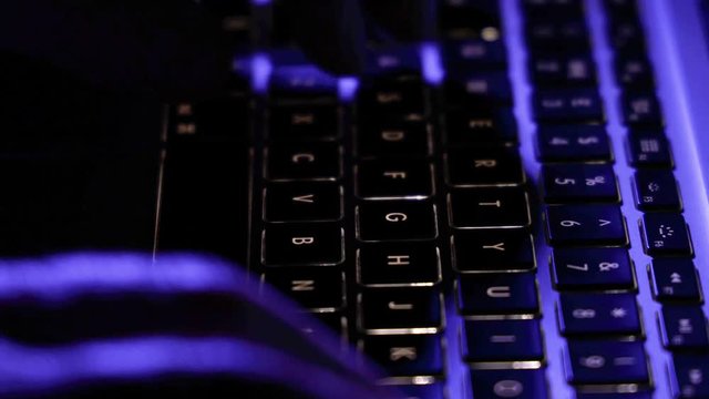 Man working typing on computer keyboard at night with light on