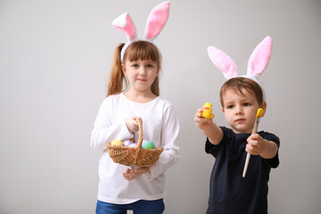 Cute little children with Easter eggs and bunny ears on light background