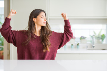 Young beautiful woman at home showing arms muscles smiling proud. Fitness concept.