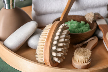 Fototapeta na wymiar Massage brushes with cosmetics on wooden tray, closeup