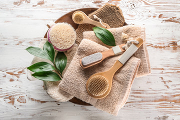 Massage brushes with towels on white wooden background