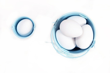 White eggs in a bucket on a white background. Concept
