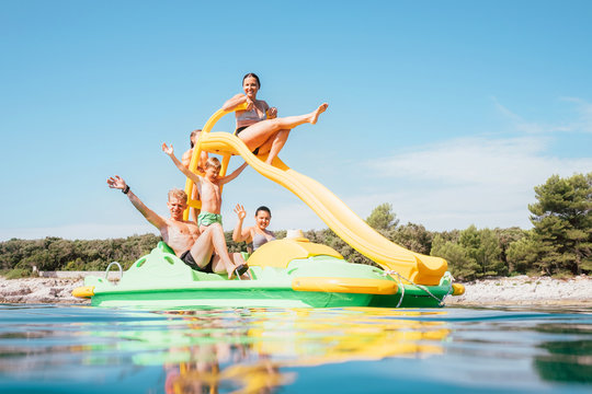 Happy family hands up on floating Playground slide Catamaran as they enjoying sea trip durins summer vacation