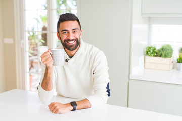Handsome man smiling while enjoying drinking a cup of coffee in the morning