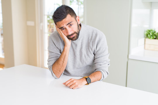 Handsome hispanic man wearing casual sweater at home thinking looking tired and bored with depression problems with crossed arms.
