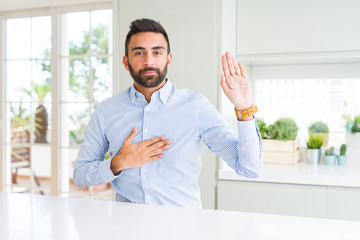 Handsome hispanic business man Swearing with hand on chest and open palm, making a loyalty promise...