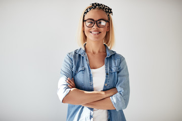 Smiling entrepreneur standing with arms crossed against a white