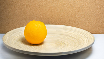 Fresh ripe orange in a wooden plate.
