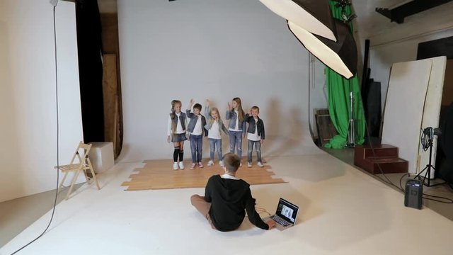 Photographer taking pictures of happy children posing in photo studio. Children's photo session