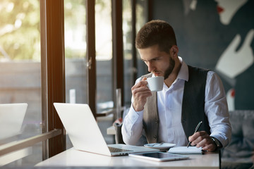 Young man drawing template for the web site associated with digital marketing, current trends and tendencies of UX / UI design. Businessman who rules his company remotely, like a freelancer