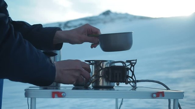 Camping in winter mountains. Climber mountaineer csitting in chair ooking outdoor in winter. Tourist backpacker travelling in winter, high snow mountains , trekking and camping equipment, camping tent