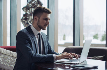 Young businessman working on a plan of Internet project on the laptop. Man discusses business matters by phone. Working computer for internet research. Digital marketing. Development