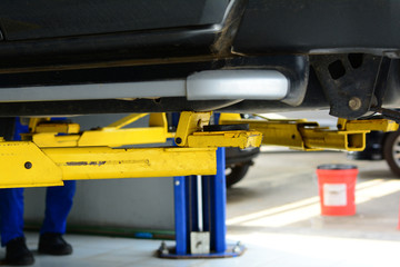 the black car chassis on yellow metal  hand lift in repair shop