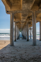 Concrete pillars underneath a long pier on the beach