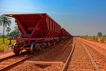 A freight train carrying bauxite in railway carriages for transhipment into a capesize bulk carrier ships by covered conveyor belt mechanism in the Kamsar, Guinea, Africa.