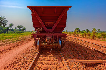 A freight train carrying bauxite in railway carriages for transhipment into a capesize bulk carrier ships by covered conveyor belt mechanism in the Kamsar, Guinea, Africa.