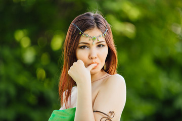 Beautiful young asian woman eating fresh kiwi, holding thumb close to the lips