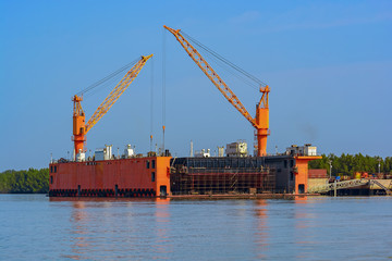 Submersible floating dry dock with dock cranes moored at river bank. Guinea, West Africa.
