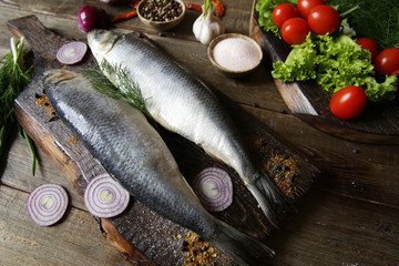 fresh two herring with onions and spices and tomato on a cutting board