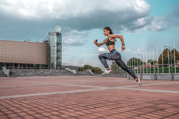 Fototapeta na wymiar Woman jump athlete girl headphones with phone listens music, while jogging summer city, sportswear leggings top. Free space. Concept healthy lifestyle, motivation. Emotions confidence strength speed.