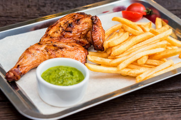 Close up meal with chicken thigh, french fries, chili pepper and garlic