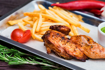 Close up meal with chicken thigh, french fries, chili pepper and garlic