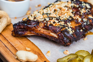 Close up board with pork ribs grilled with BBQ sauce, peanuts and jalapeno