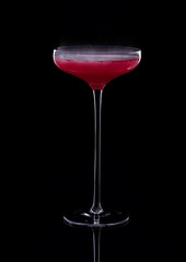 Cocktail based on carbonated drink in a beautiful glass on a thin long leg isolated on black with reflection.