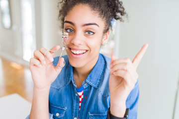 Young african american girl using eyelashes curler very happy pointing with hand and finger to the side