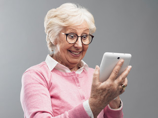Happy surprised senior lady using a digital tablet