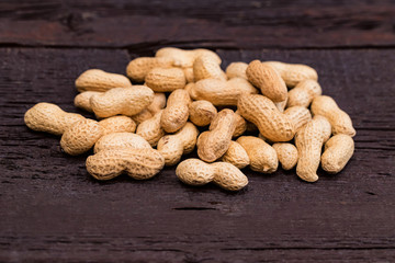 Close up pile of unpeeled peanuts on dark wooden background