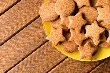Top view of freshly made cookies in a yellow plate on a wooden table. Empty space for text