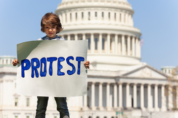 Boy manifesting holding sign saying protest in hands