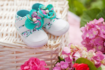 Obraz na płótnie Canvas Cose-up of baby girl shoes. Outdoor background with flowers