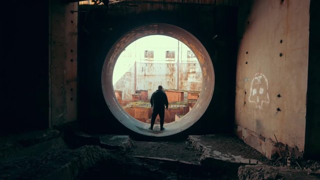 Man traveller and explorer inside round door or gate to abandoned nuclear rector or generator room in ruined and destroyed Crimean Nuclear Power Plant