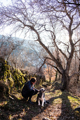 Fototapeta premium Woman with her dog in the forest enjoying sunset time.