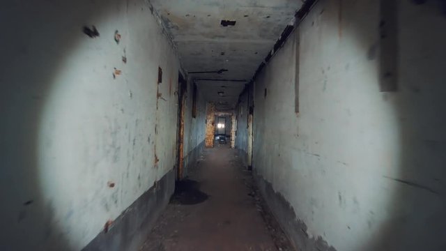 Moving through dark creepy corridor in abandoned nuclear power plant in Crimea. First person view, going with flashlight in dirty grunge tunnel in ruined building, horror escape concept