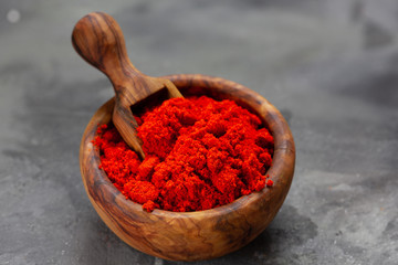 Chili powder in wooden bowl on dark background