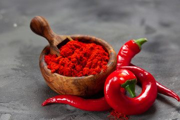 Chili powder in wooden bowl on dark background