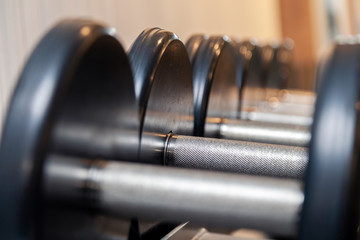 Closeup oshiny metal dumbbells, barbells, weights on the stand in modern gym of hotel. Сoncept of healthy lifestyle, weight loss, training, bodybuilding, bodyfitness, diet, sport exercises