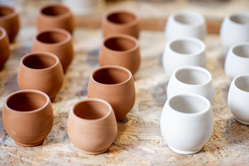 Close-up of clay pitchers before baking on the shelves at the pottery