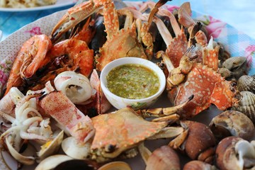 Grilled seafood with spicy sauce, mix grill with crab, shrimp, shell and squid. Food concept.