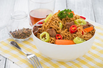 Chinese noodles with beef, muer and vegetables close-up on a plate
