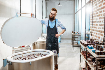 Handsome man as a worker or business owner standing near electric ovens for ceramics at the pottery...