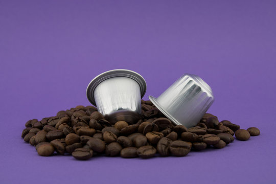Coffee capsules or coffee pods on coffee beans, purple background. Capsules.