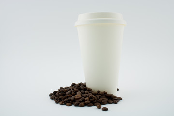 Paper coffee cup on coffee beans, white background. The coffee cup is covered.