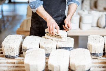 Male worker getting clay products from the gypsum forms at the pottery manufacturing, close-up view