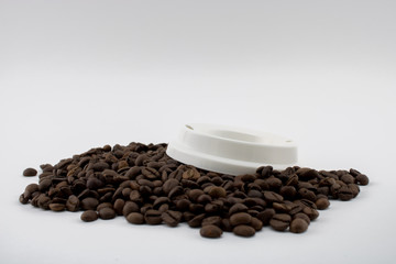 Lid of paper coffee cup on coffee beans, white background.
